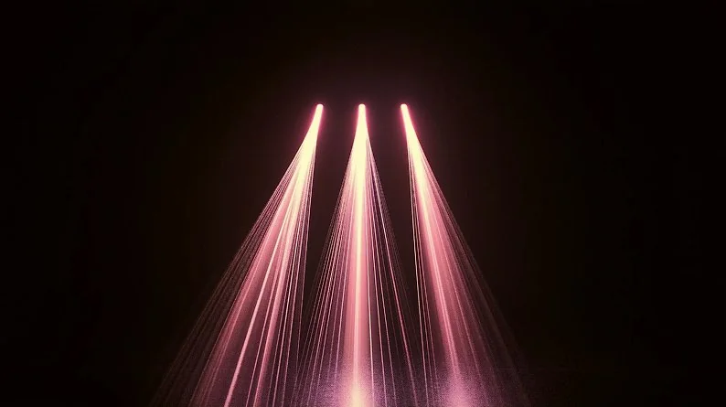 Three soft pink light beams converging downward from above against a dark background, creating a dramatic spotlight effect, symbolizing the three components of tradeshow campaign tracking.