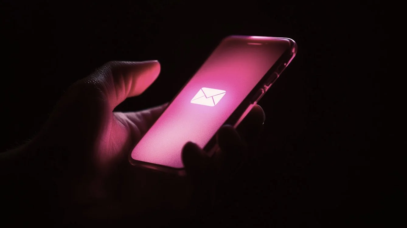 Hand holding a smartphone with a glowing pink screen displaying an email follow-up to tradeshow networking.